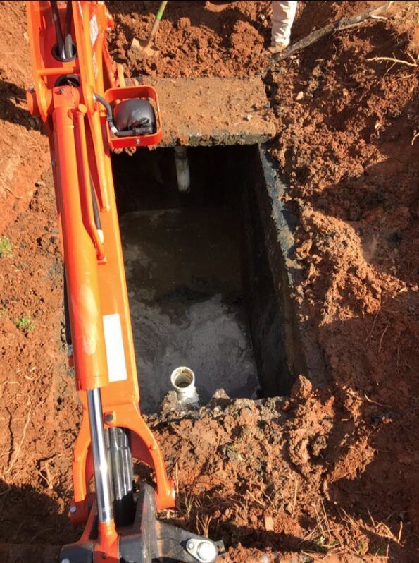 An orange excavator is digging a hole in the ground