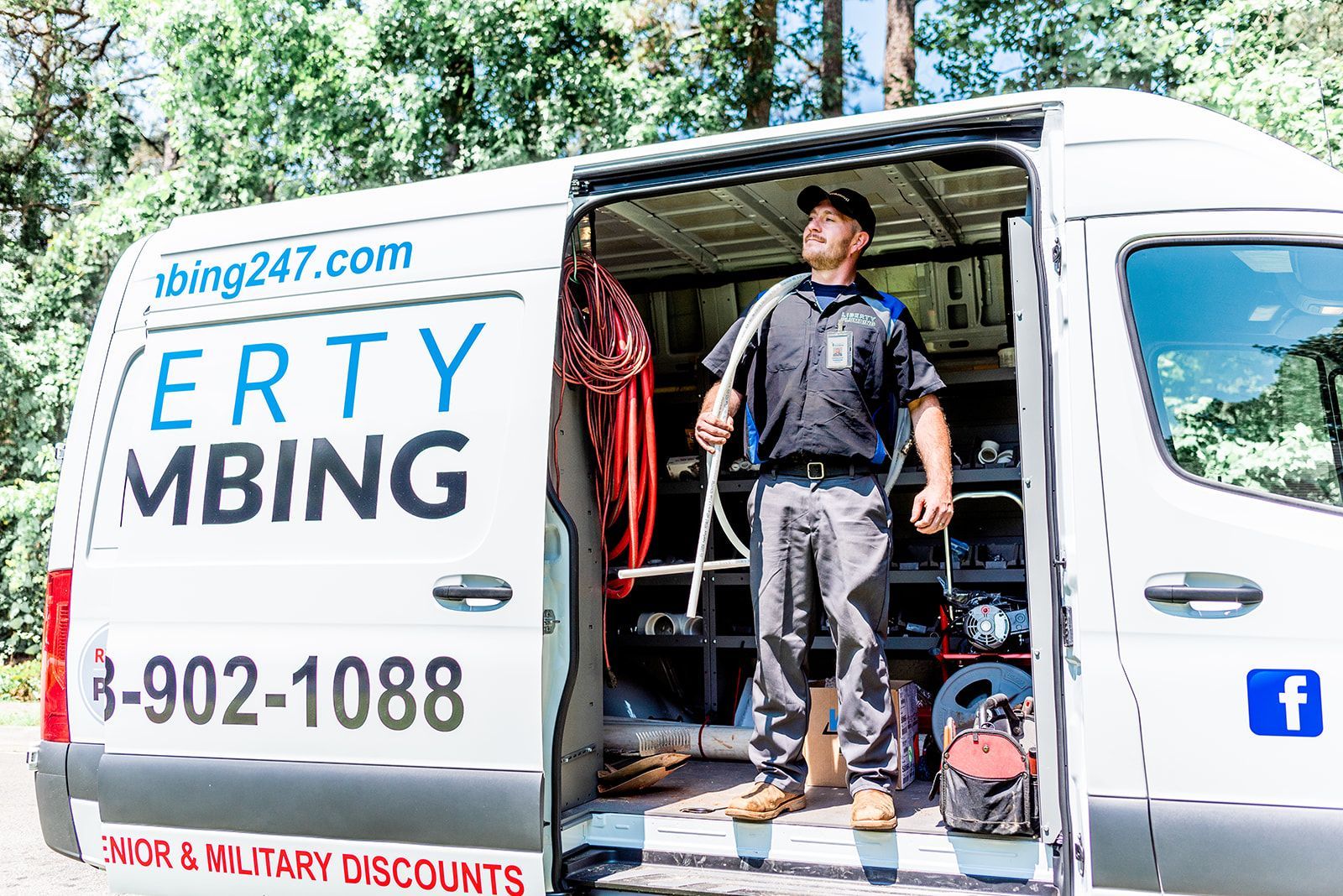 A man is standing in front of a van with the door open.