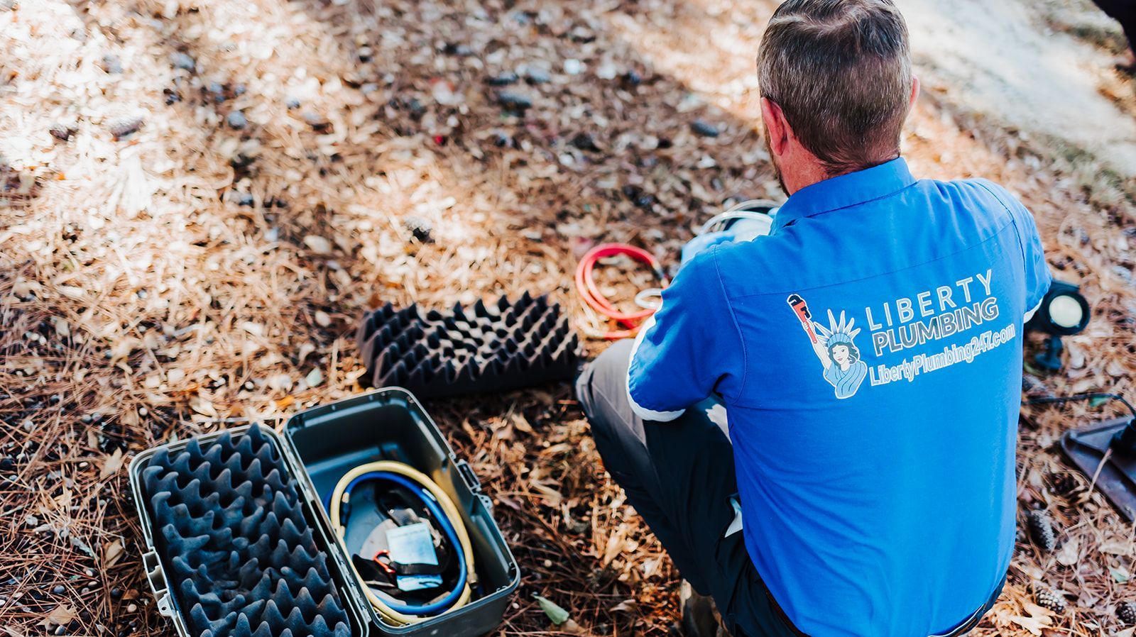A white pipe is laying in the dirt next to a rock.