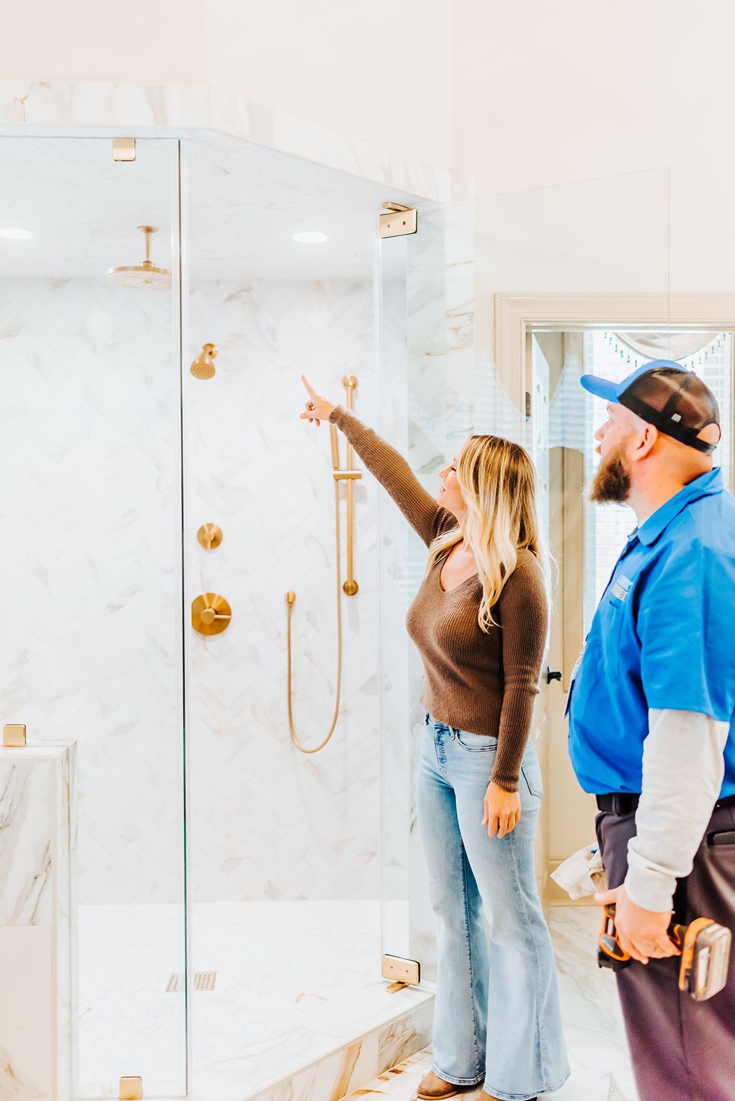 A man is talking on a cell phone under a sink with water coming out of it