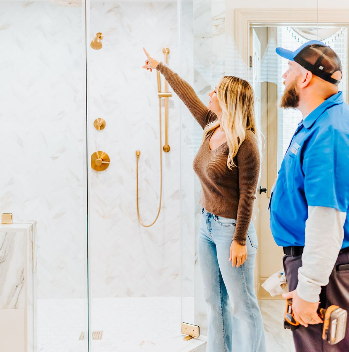 A man is talking on a cell phone while looking at a leaking pipe