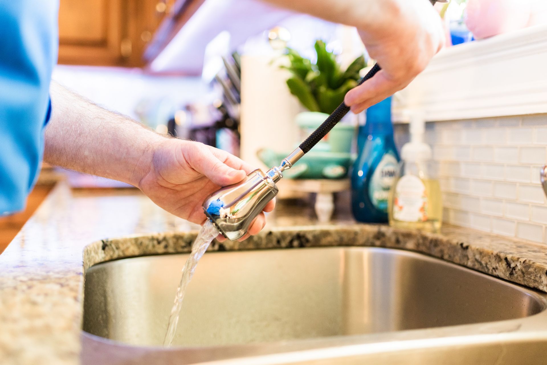 A person is washing a brush in a kitchen sink.