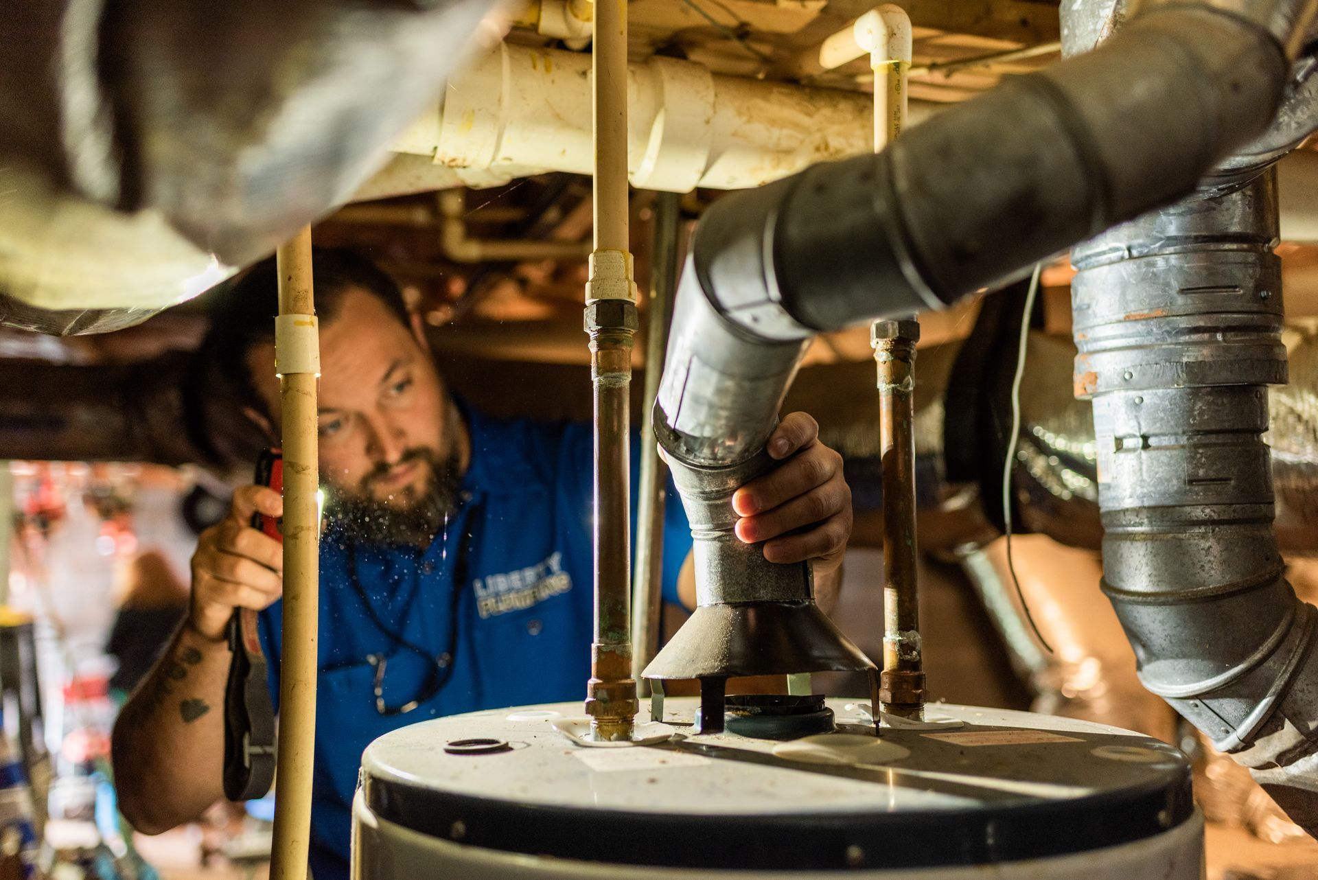 A person is working on a water heater with a danger sign on it