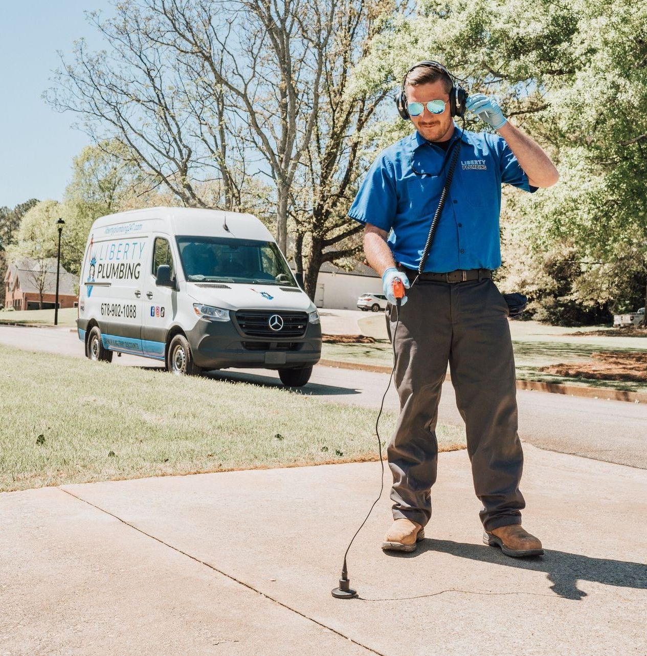 A man wearing headphones stands on a sidewalk in front of a mercedes van