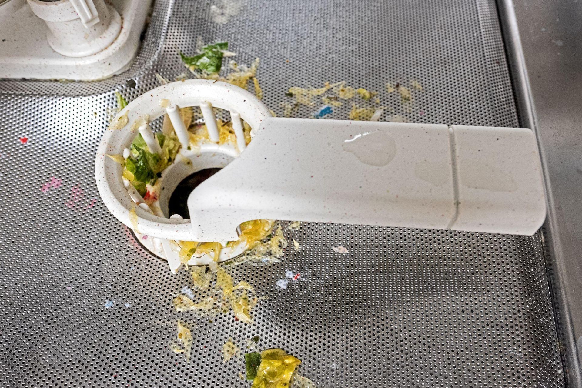 Dishwasher drain with bits of food and debris trapped in it