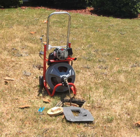 A drain cleaner is on a cart in the grass