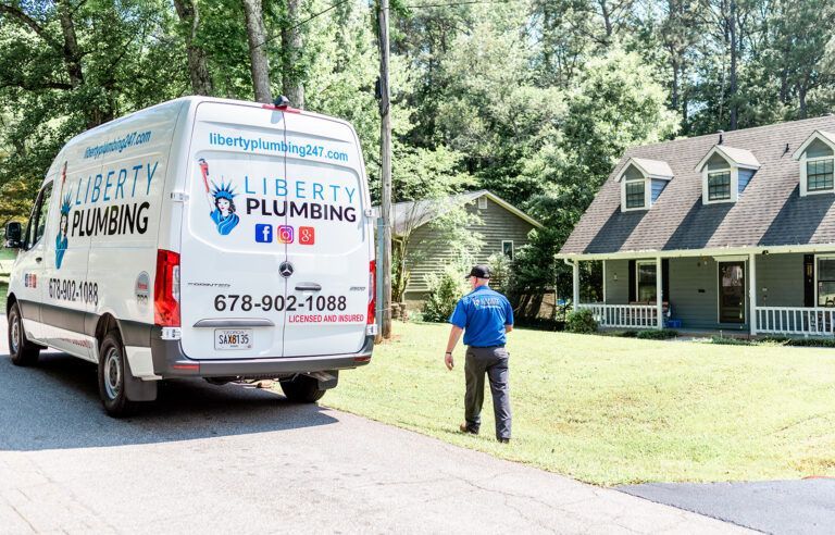 A liberty plumbing van is parked in front of a house.