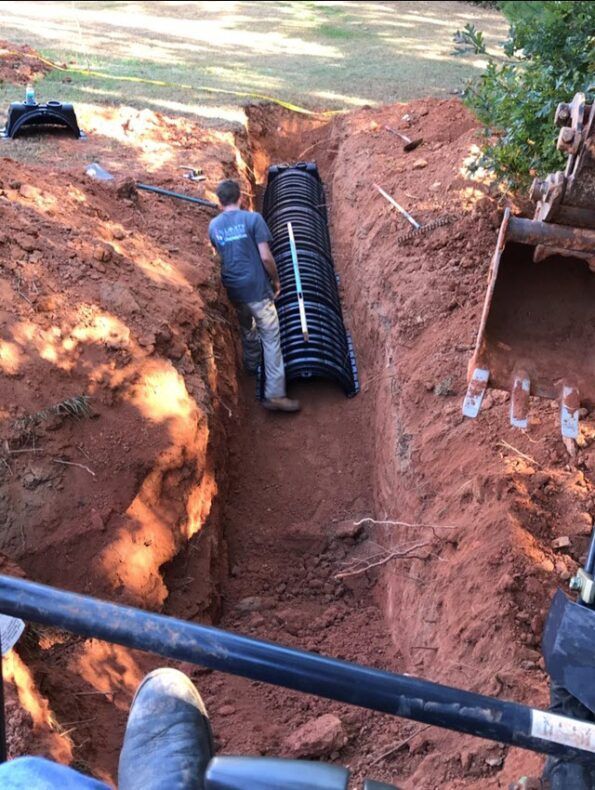 A man is working on a septic system in a trench.