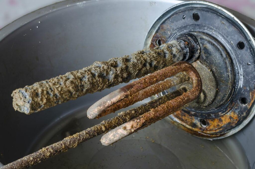 A close up of a rusty water heater in a pot of water.