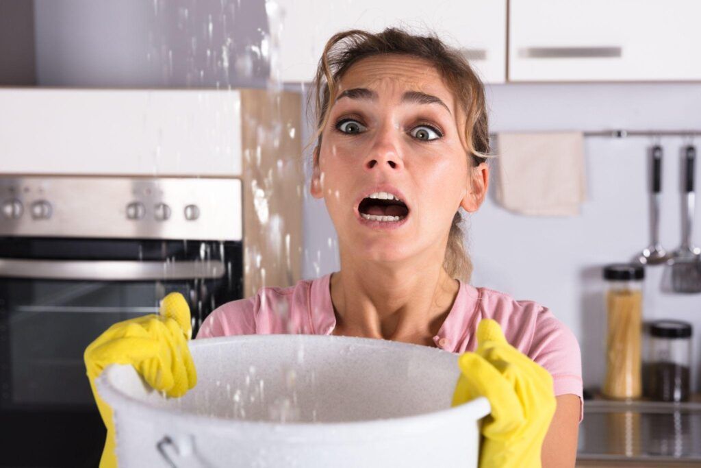 A woman is holding a bucket of water in a kitchen.