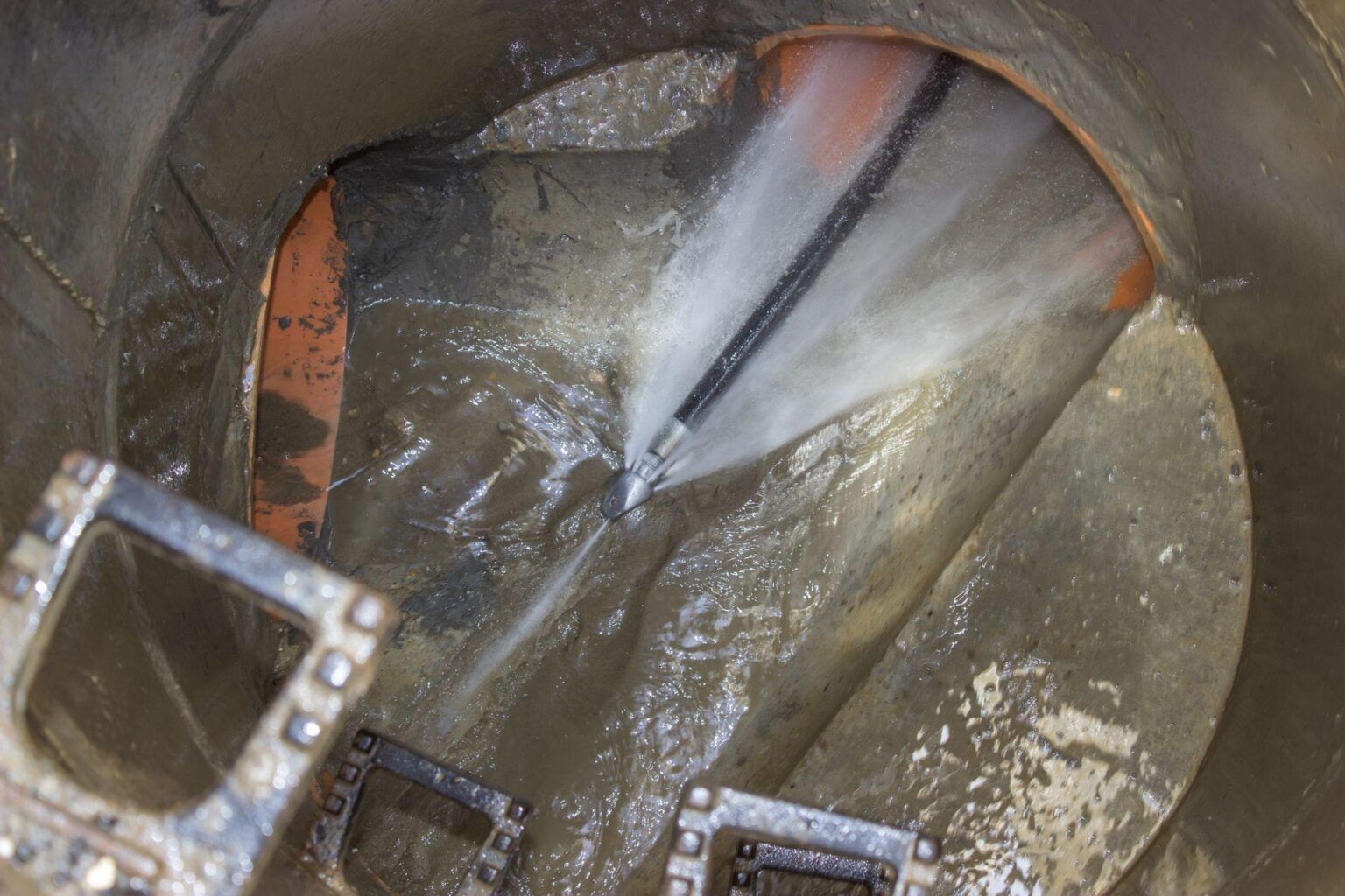 A hose is spraying water into a drain.