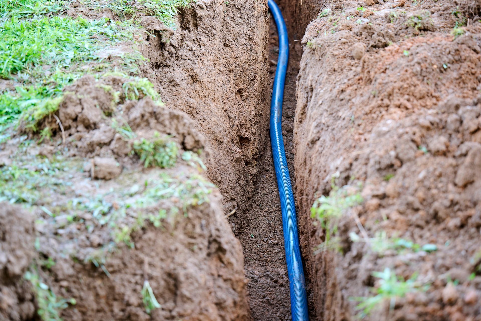 A white pipe is laying in the dirt next to a rock.