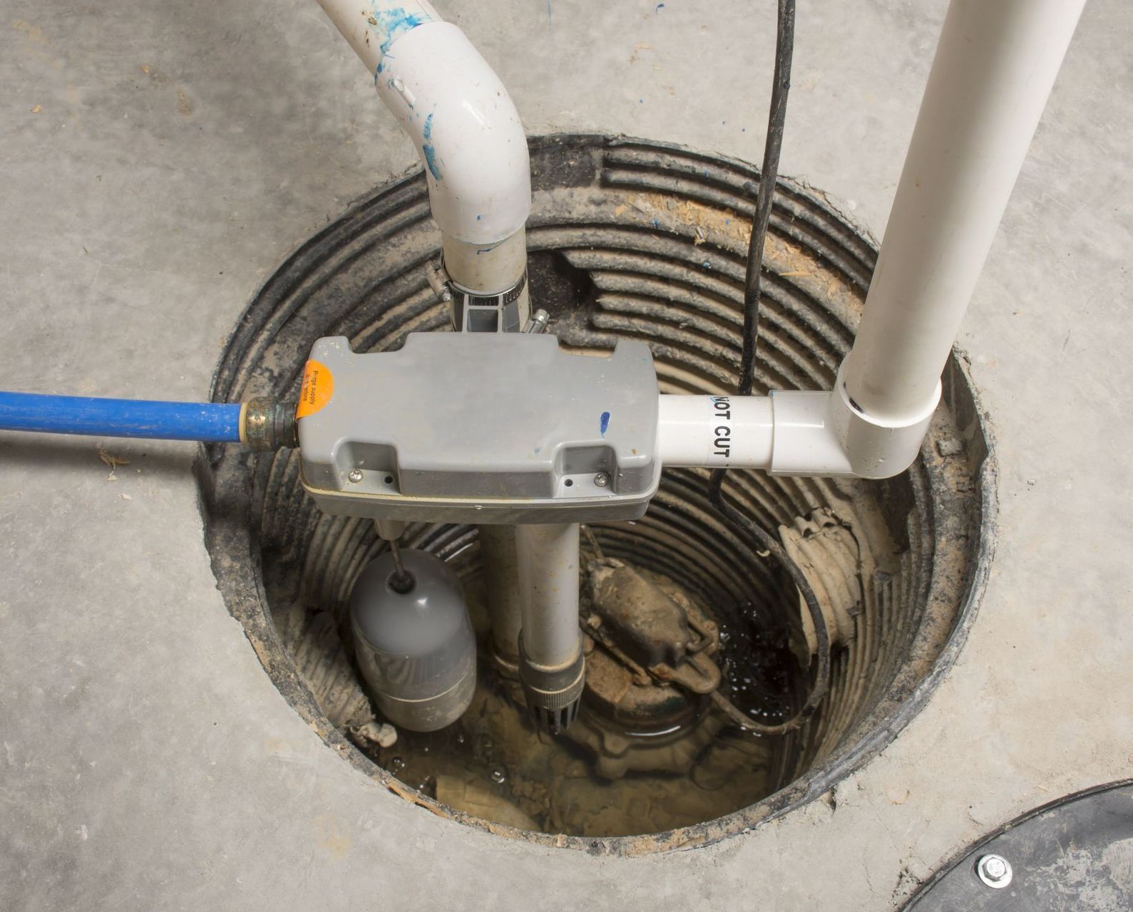 A close up of a basement drain with pipes coming out of it.