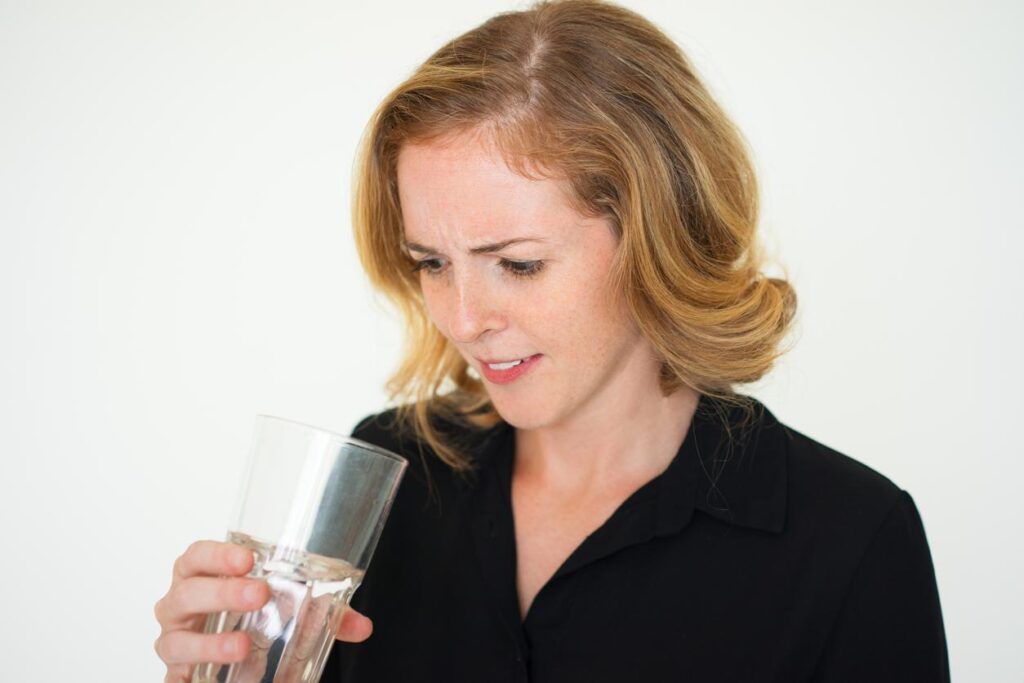 A woman is drinking a glass of water.