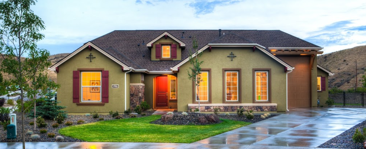 A large green house with a gray roof and a concrete driveway.