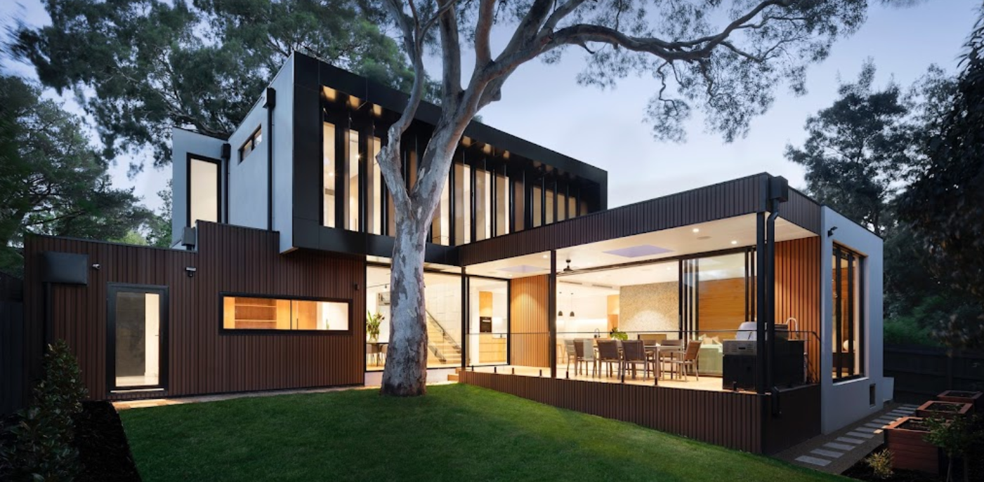 A modern house with a lot of windows and a tree in front of it