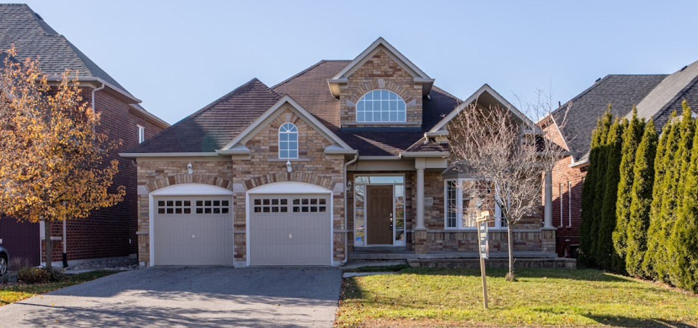 A large brick house with two garage doors in a residential area.