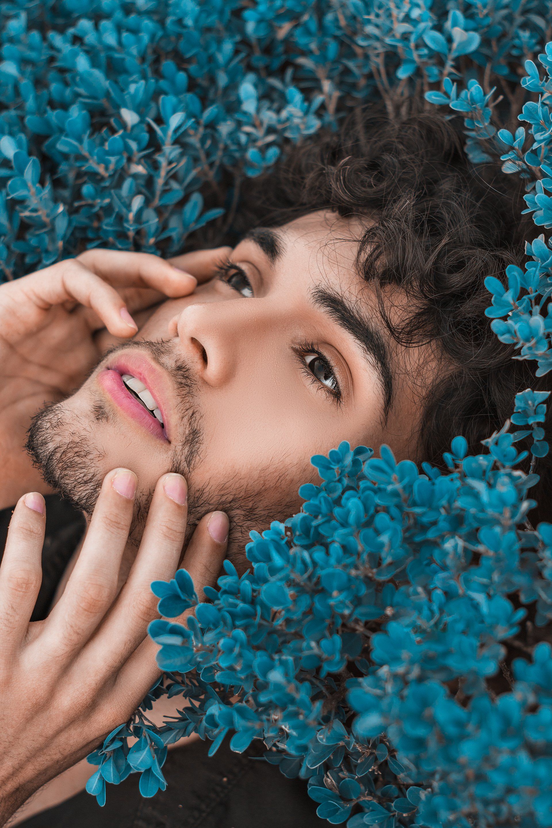 Male Touching Face Laying in Blue Flowers