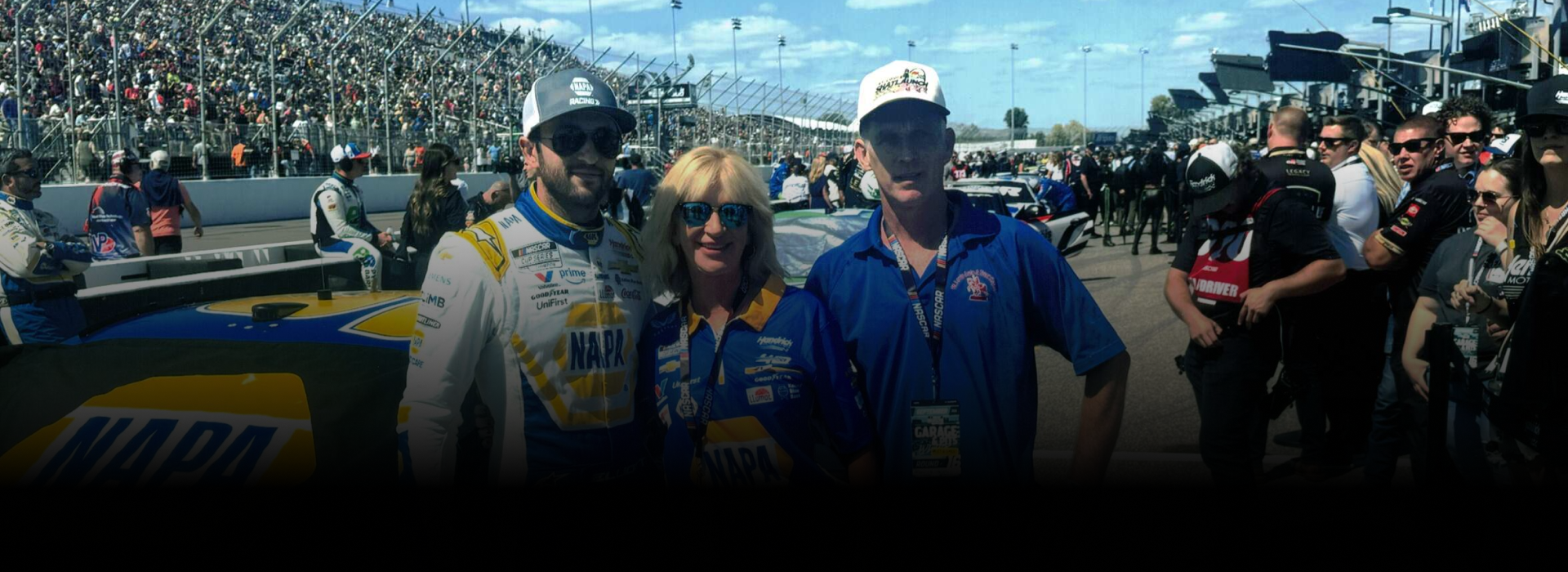 Three people posing at a race. Two are wearing team attire, with a race car behind them.  | St. Louis Auto & Truck Repair