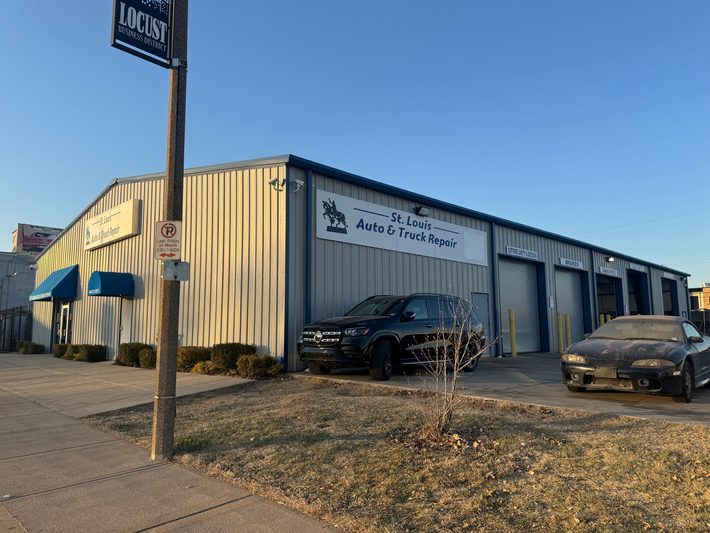 A car repair shop with a metal exterior, a sign, and two vehicles parked outside. | St. Louis Auto & Truck Repair