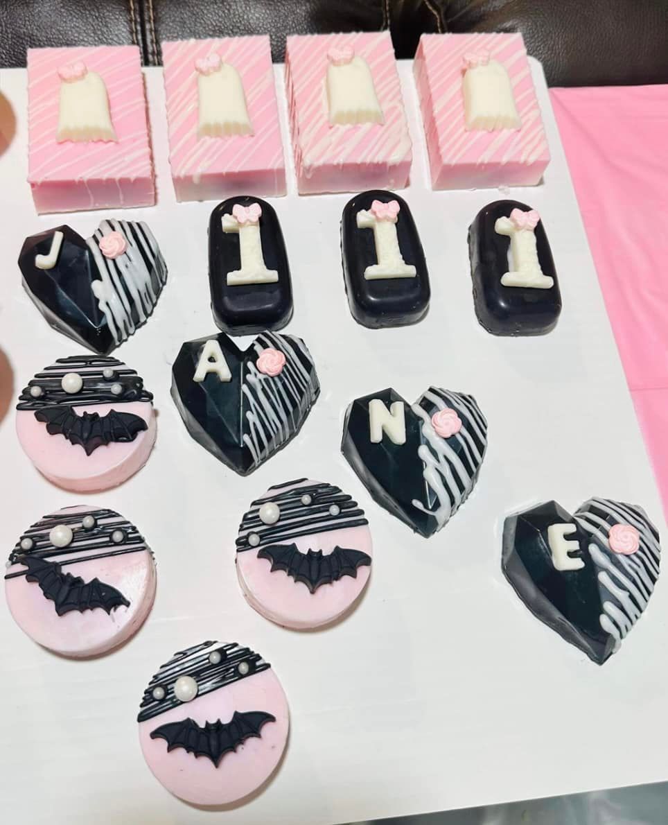Rows of decorated chocolates: pink dresses, letters I, A, N, E, and bats.
