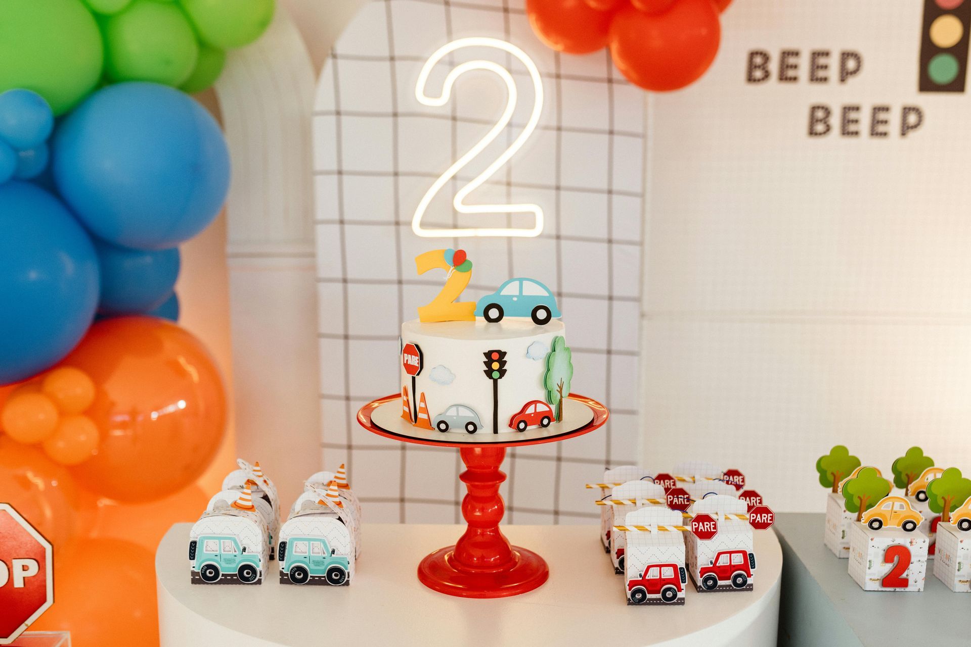 Car-themed second birthday party with cake, balloons, and treats.