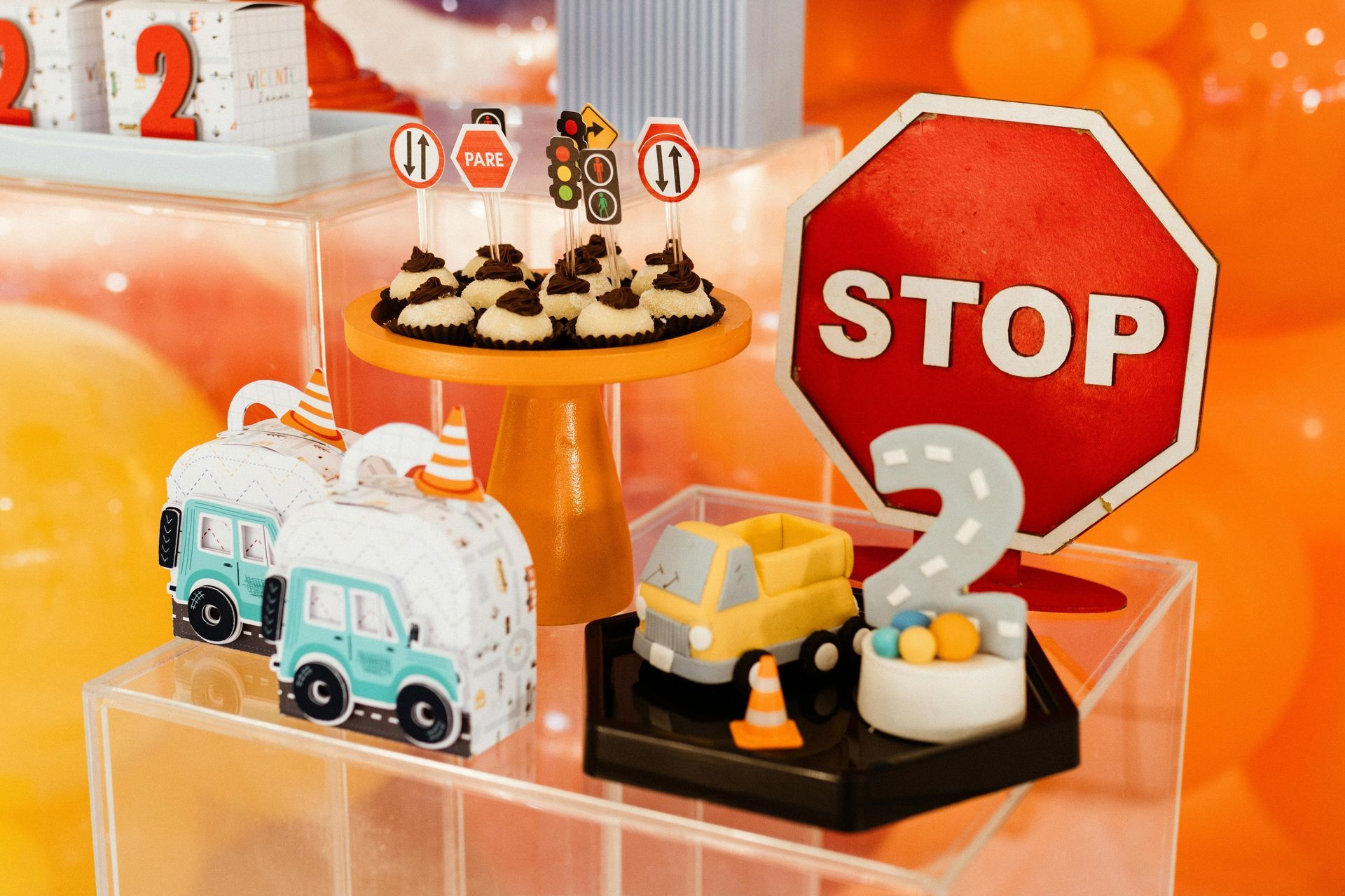 Construction-themed birthday treats: cupcakes, truck cake, stop sign, and toy cars on a decorated table.