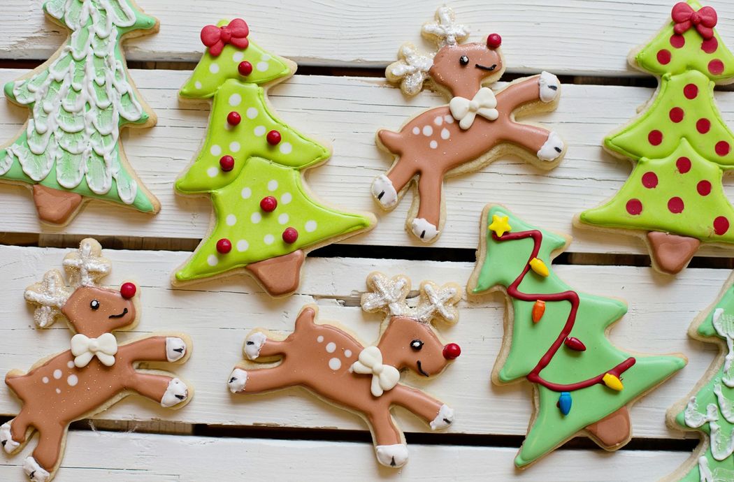 Christmas cookies: decorated reindeer and Christmas trees on a white wooden surface.
