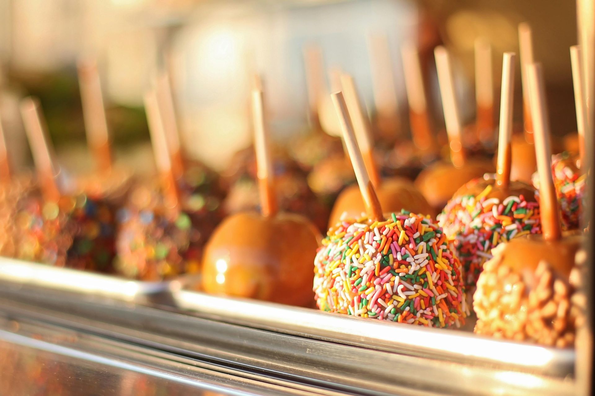 Caramel apples with sprinkles on display in a glass case.