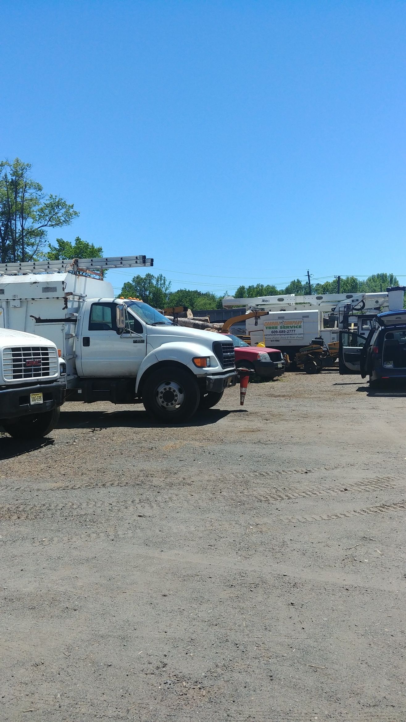 A Row of Trucks Are Parked in A Gravel Lot – Lawrence Township, NJ – Carroll Tree Service