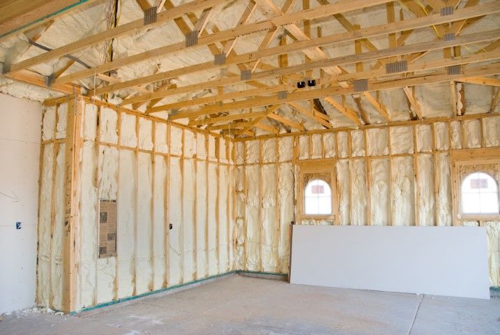 Garage interior with exposed wooden framing and walls insulated with spray foam.