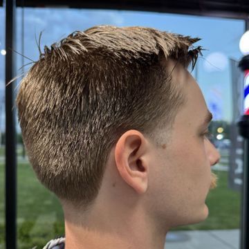 A young man is getting his hair cut at a barber shop.