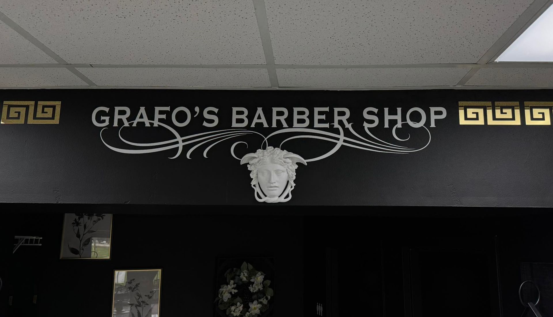 A sign for grafo 's barber shop with a medusa on it