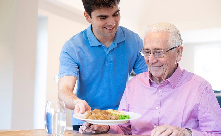 Professional Assistant Serving Meal To Old Man — Lawrenceville, GA — Professional and Quality Home Care