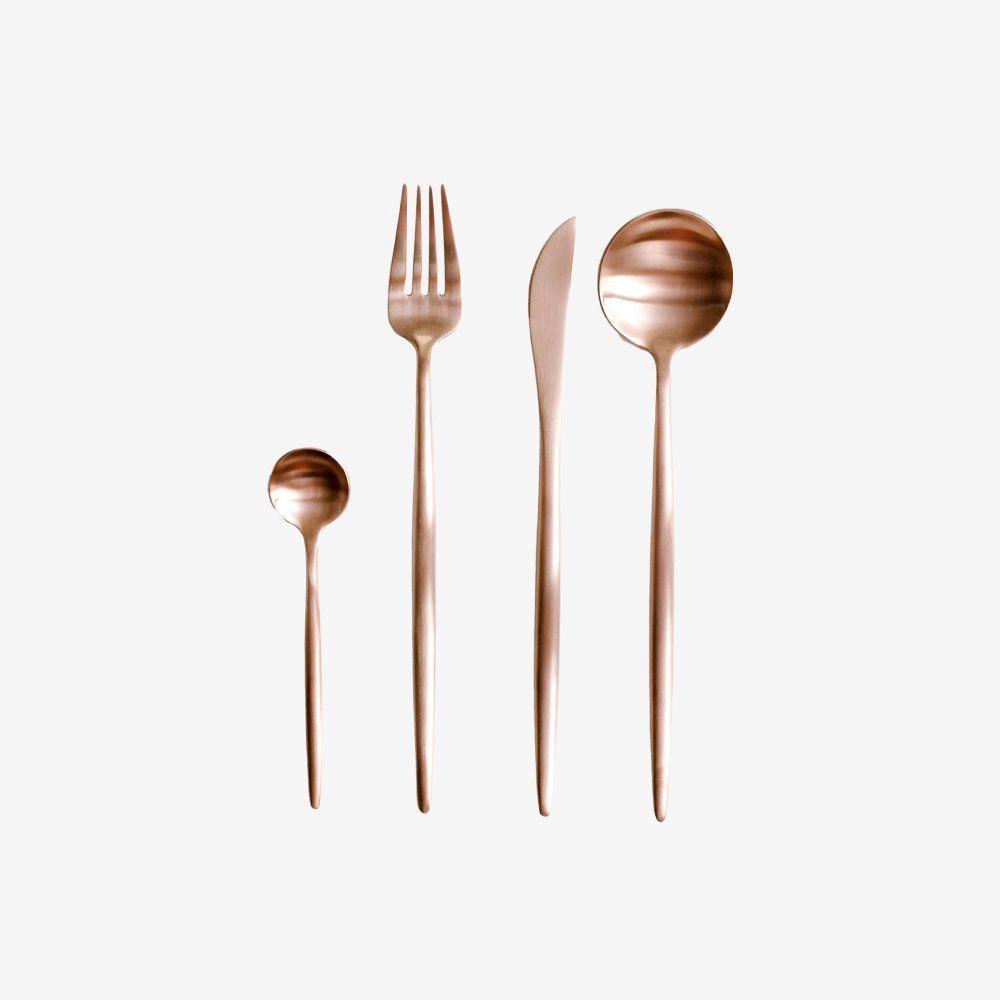 Copper-toned spoon, fork, knife, and large serving spoon arranged vertically on a white background