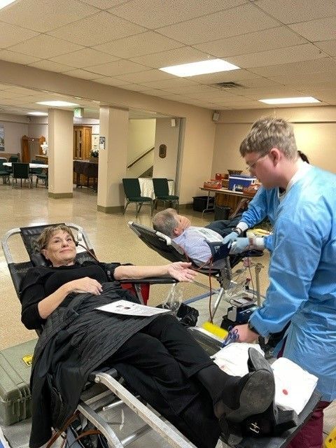 A woman is laying in a hospital bed while a man stands behind her