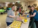 A group of people are preparing food at a table in a room.
