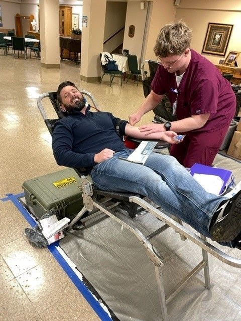 A man is laying in a chair while a nurse holds his arm