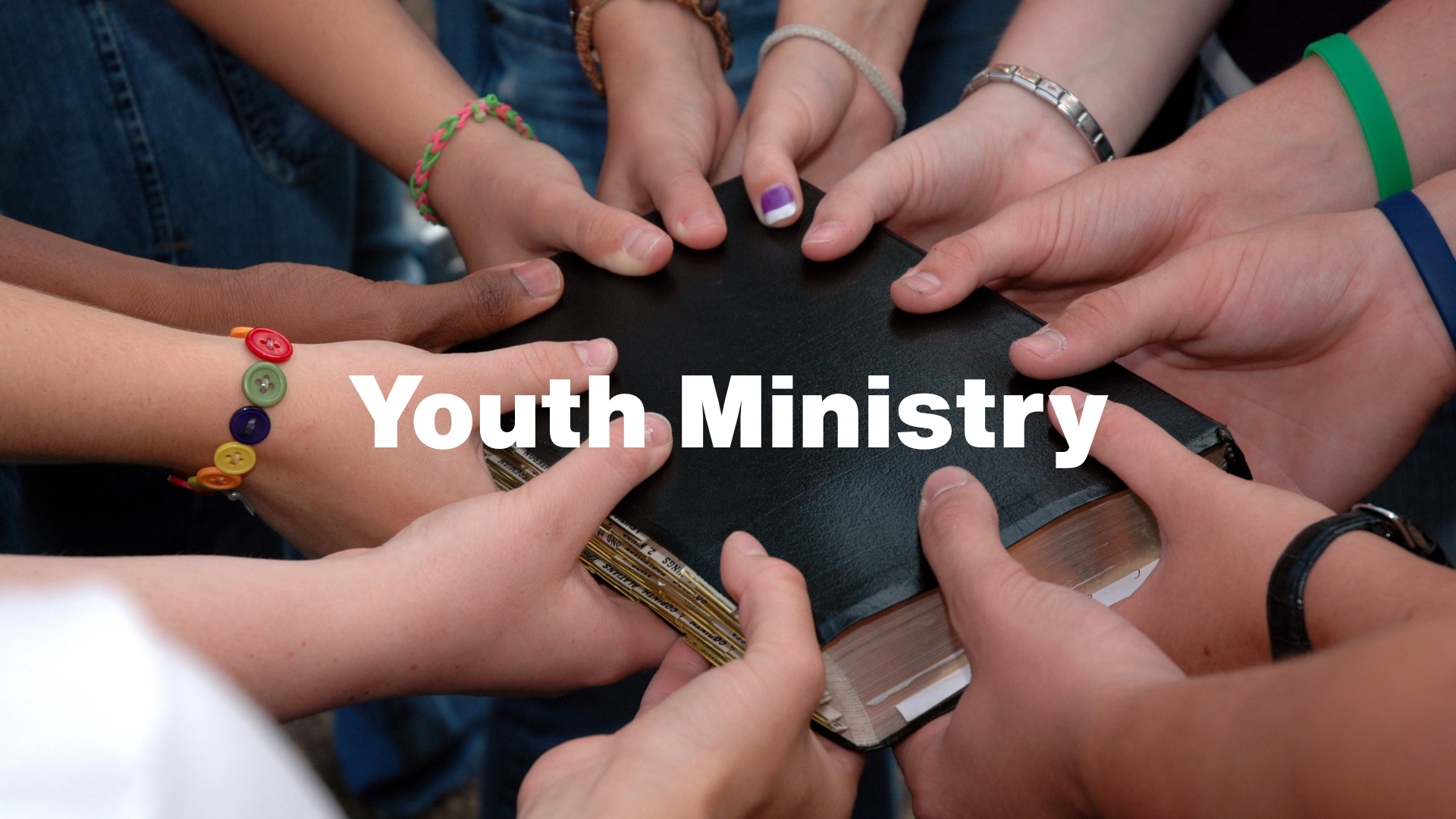 Hands of young people surrounding a Bible, labeled