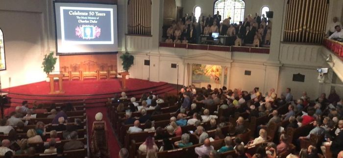 A large group of people are sitting in a church watching a presentation.