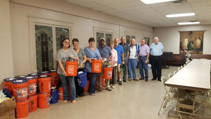 A group of people are standing in a room holding buckets.