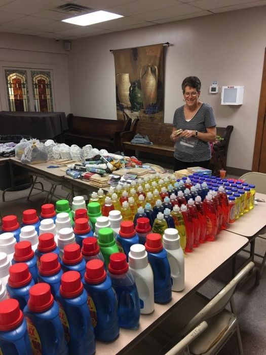 A woman stands behind a table full of bottles of laundry detergent