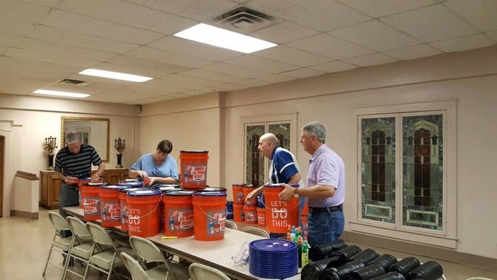 A group of men are standing around a table filled with buckets.