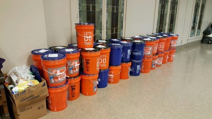 A bunch of orange and blue buckets are stacked on top of each other in a room.