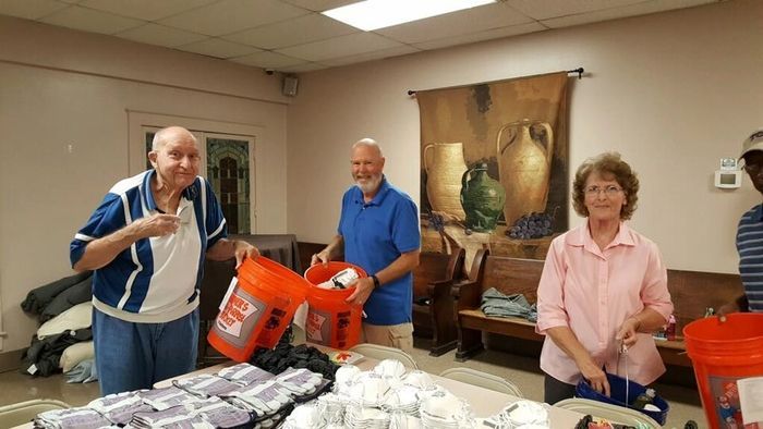 A group of people are standing around a table holding buckets.
