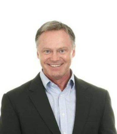 A man in a suit and blue shirt is smiling for the camera.