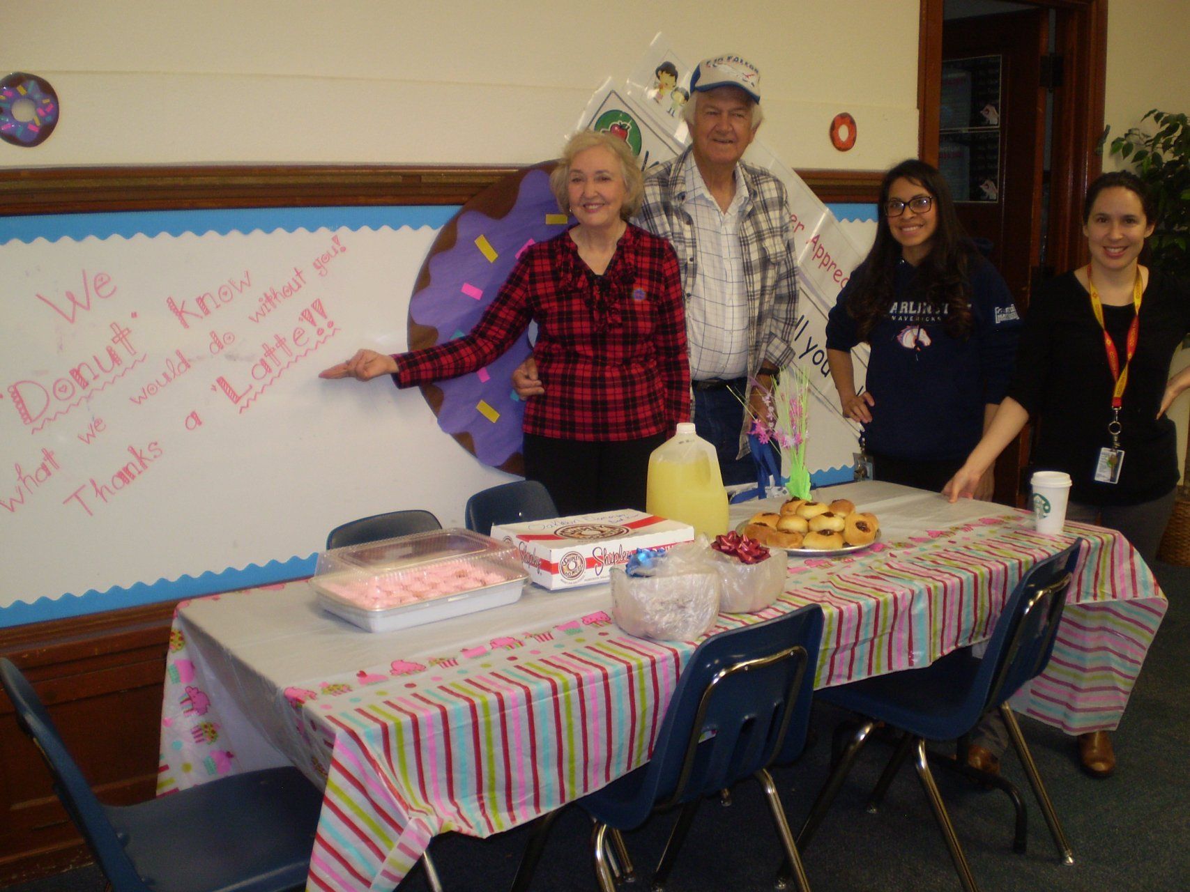 A group of people standing around a table with a donut on the wall