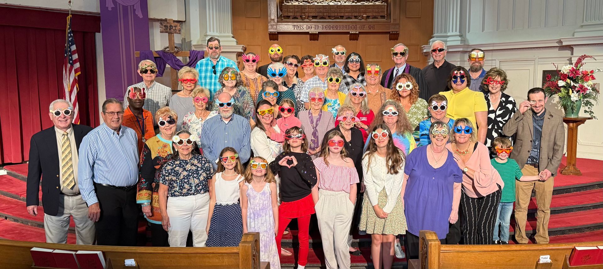 Group of people in a church wearing novelty sunglasses posing for a photo.