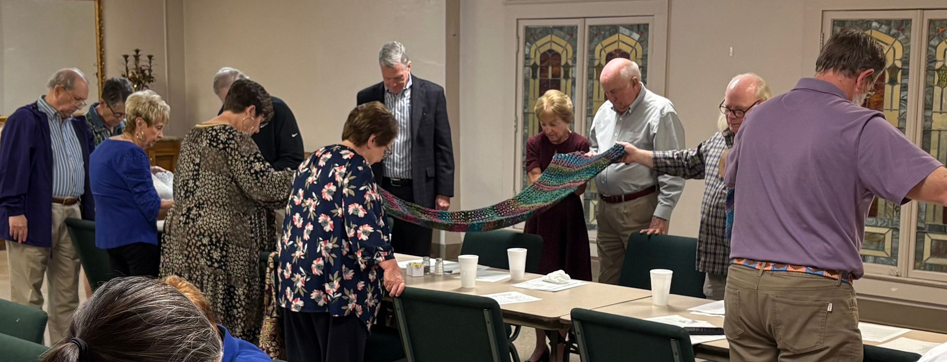 People with raised hands, possibly in worship, against a blurred blue background.