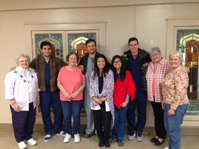 A group of people posing for a picture in front of a window